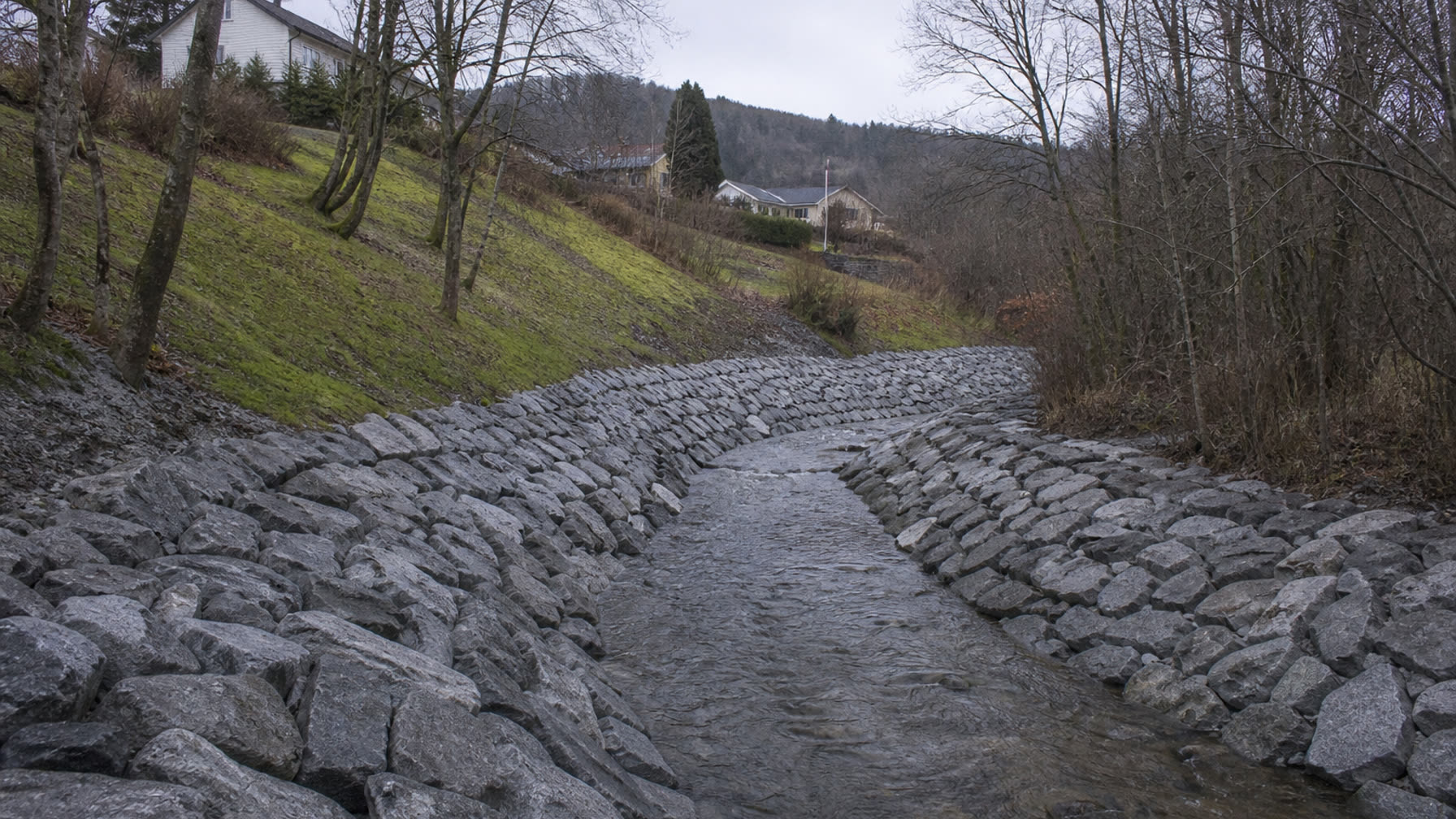Elveløp der elvebredden er sikret med grov sprengstein (plastring) og bevart vegetasjon